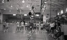 Unidentified female collegiate player demonstrates layups for girl campers.