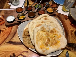 Choice of Five Breads and with all Nine Accompaniments - Traditional Naan, Garlic-Ginger Naan, Spiced Naan, Onion Kulcha, or Paneer Paratha. Accompaniments - Cucumber Raita, Roasted Red Pepper Hummus, Mango Chutney, Tomato-Date Jam, Tamarind Chutney, Coriander Chutney, Garlic Pickle, Red Chile Sambal, or Spicy Jalapeño-Lime Pickle