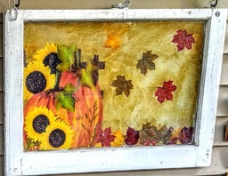 The pumpkin and flowers were cut out from a garden flag.  The falling leaves were table decorations.  Tissue paper was used for the background. All was decoupaged on an old window