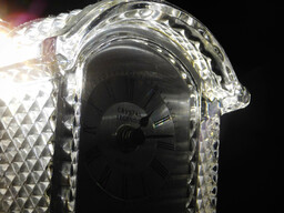 Light filtering through the prismatic surface of a glass clock.