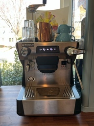 This is a one-group espresso machine, meaning that it has one portafilter spot and can pull one shot of espresso at a time. The knob on the left side of the image allows the user to dispense hot water. The right side of the image has a steam wand, which is used to steam milk for drinks.