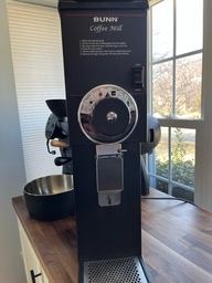 This is a grinder that would be used in a commercial setting. It can grind large amounts of coffee beans at a time and a bag can be attached to the front to catch the ground coffee.