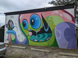 Patch Whisky is a well-known street artist in the Charleston, South Carolina area. This work is a mural painted by Patch Whisky on New Life Auto Sales at 5103 Dorchester Road. The mural is a monster smiling at a butterfly perched on one if its tentacles. 