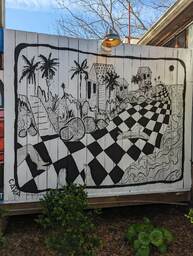 The Charleston Pour House is a live music venue located at 1977 Maybank Highway in James Island, SC. This mural by Cara of @house.of.cara is black and white and depicts a long beach scene. There is checkerboard sand, finely lined waves, wonky trees and houses. 