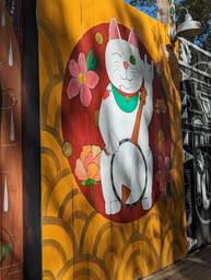 The Charleston Pour House is a live music venue located at 1977 Maybank Highway in James Island, SC. This mural by @ironabz is of a cat holding up the "rock on" sign of the pointer finger and pinkies as the only fingers raised, and in the other hand a banjo. 