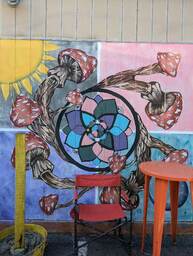 The Charleston Pour House is a live music venue located at 1977 Maybank Highway in James Island, SC. This mural is on the side of the building and shows a swirl of mushrooms surrounding a flower, with a sun in the upper left corner of the mural.