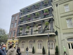 Decatur Street, view of the sidewalk.  A common sight throughout the French Quarter: long, rounded balconies with wrought-iron fencing, decorated with hanging baskets of seasonal flowers.